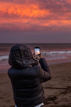 Person takes photo at Chapadmalal beach with vibrant sunset sky.