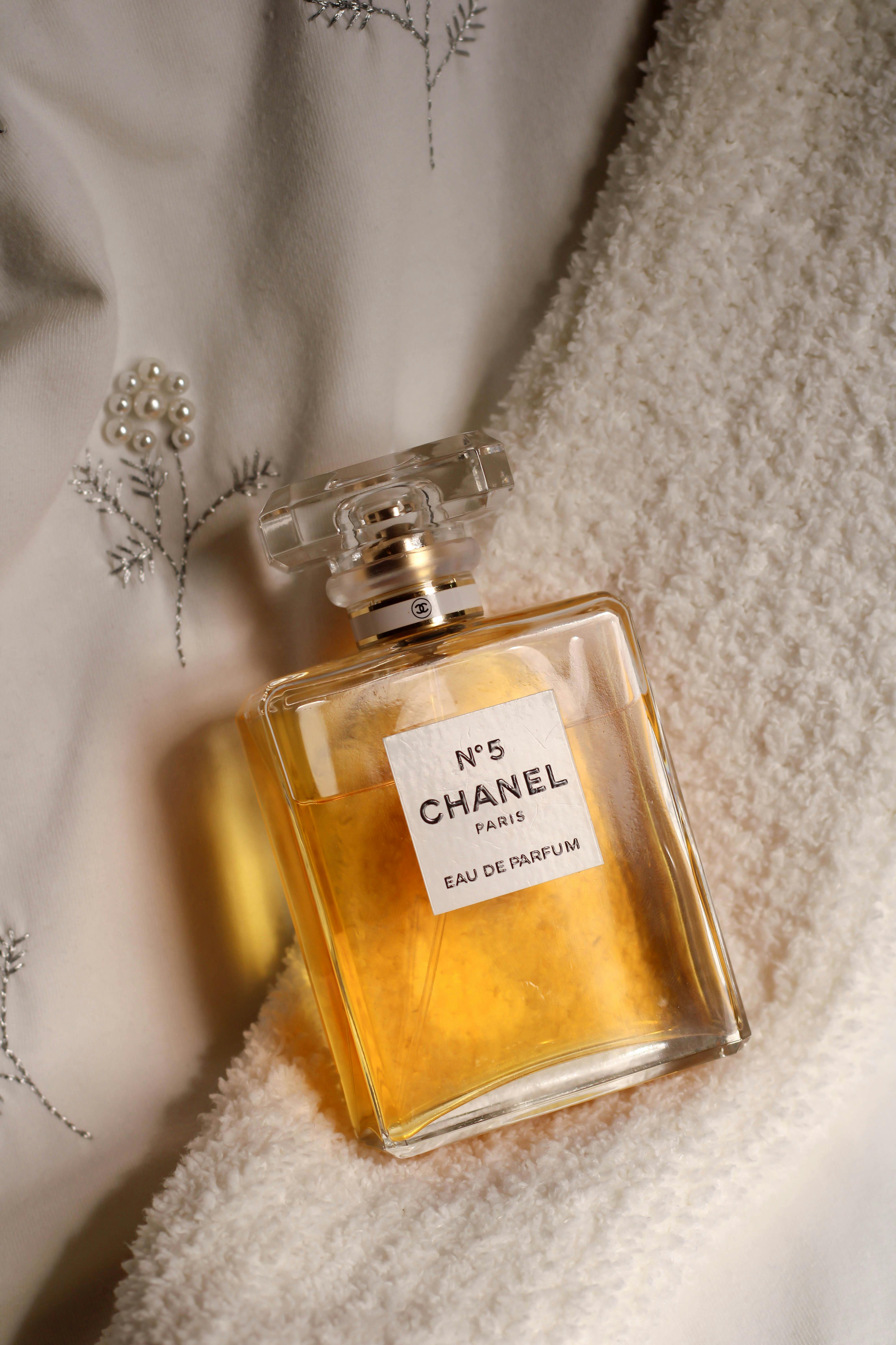 Luxurious Chanel No. 5 perfume bottle resting elegantly on white embroidered fabric.