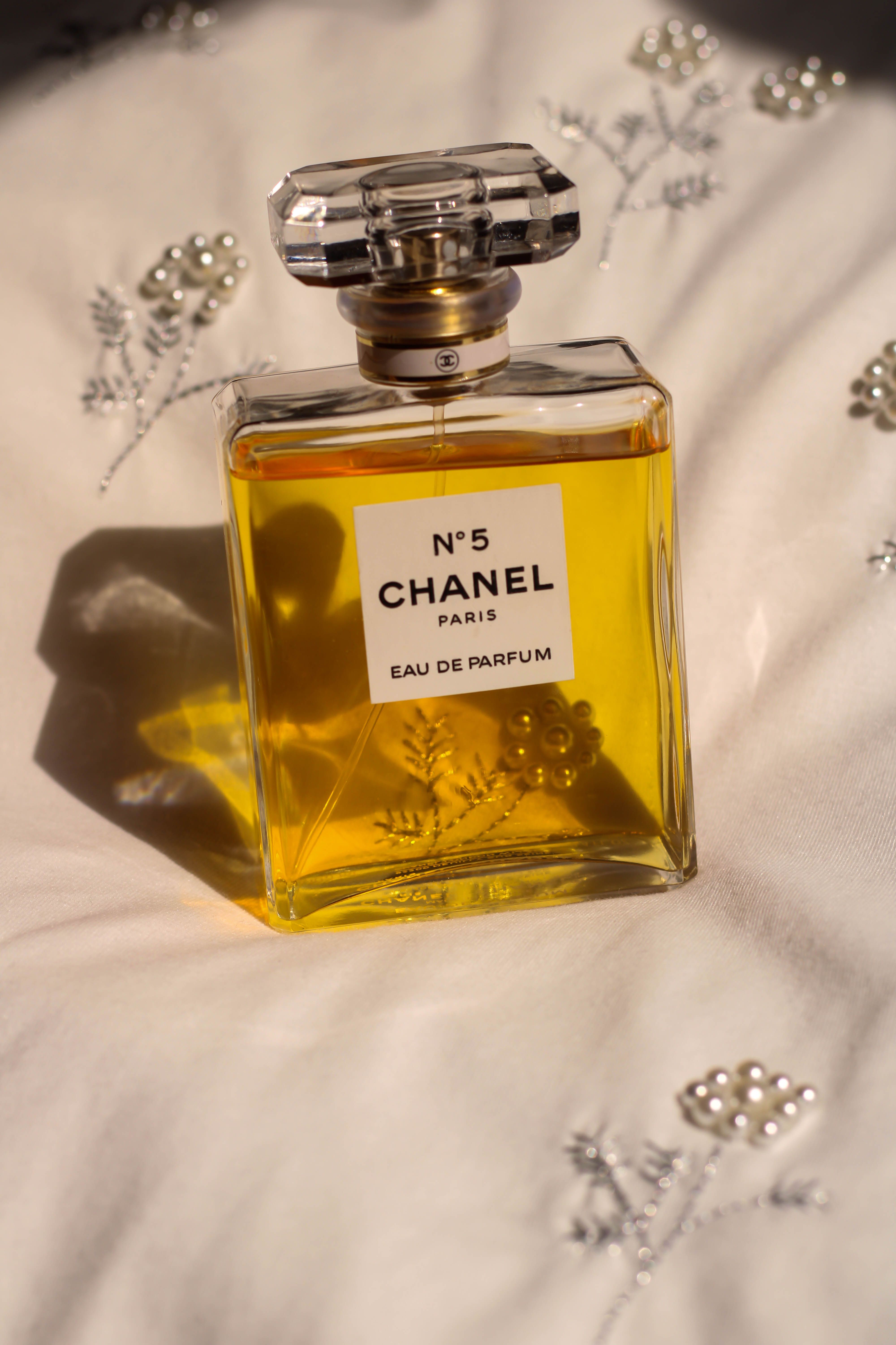 Chanel No.5 Eau de Parfum bottle on fabric with decorative pearls.