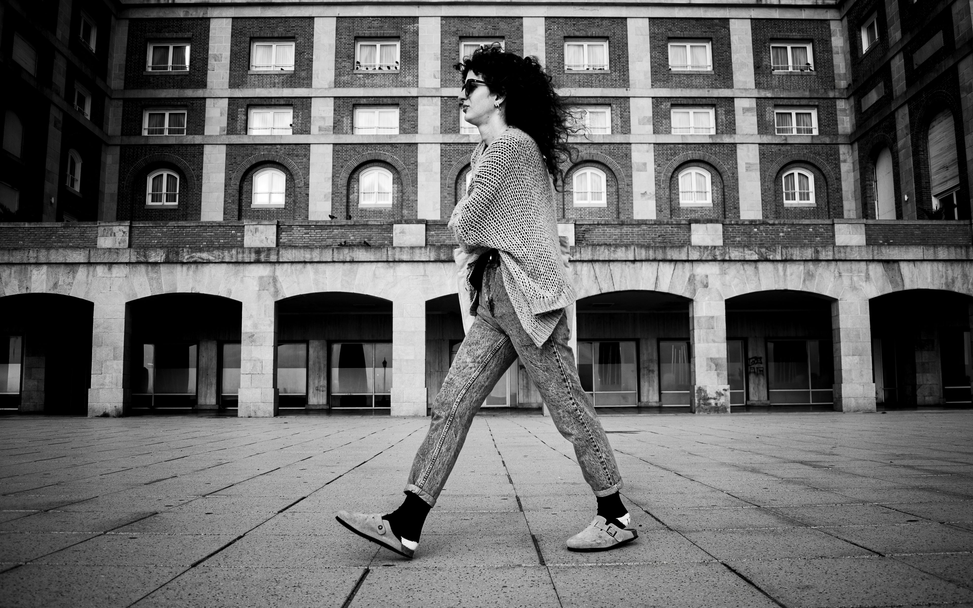 Stylish woman walking in black and white urban scene in Mar del Plata, Argentina.