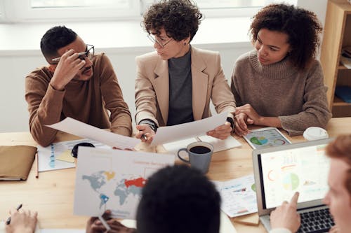 Photo Of People Sitting Near Table Holding Papers