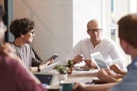 一群专业人士围坐在现代办公空间的桌子旁进行头脑风暴