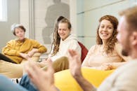 一群成年人随意地坐在室内的豆袋上交谈，分享着幸福与微笑