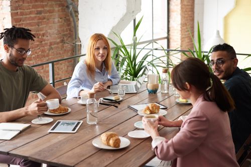 Free Team of diverse adults having a collaborative meeting with coffee and pastries in a modern office setting. Stock Photo