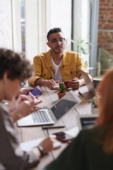 A group of professionals engaging in a team meeting around a wooden table in a modern office setting.