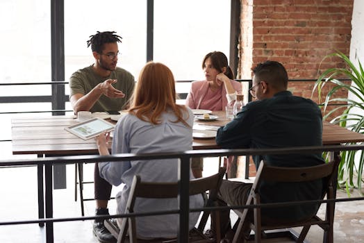 A diverse group of professionals engaged in a creative business meeting around a wooden table indoors.