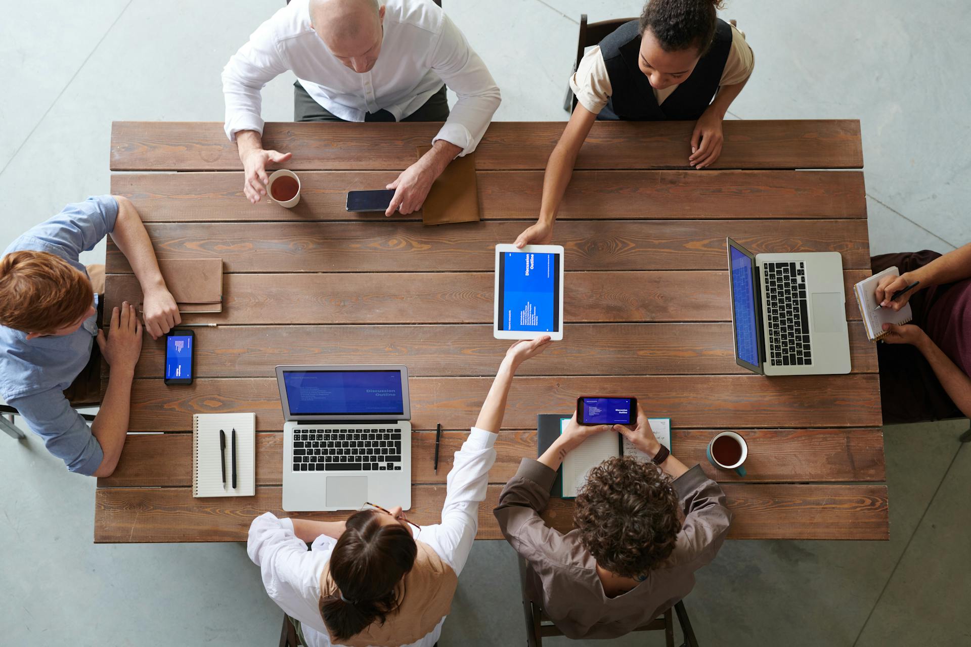 A diverse group of professionals engaged in a productive office meeting using digital devices.