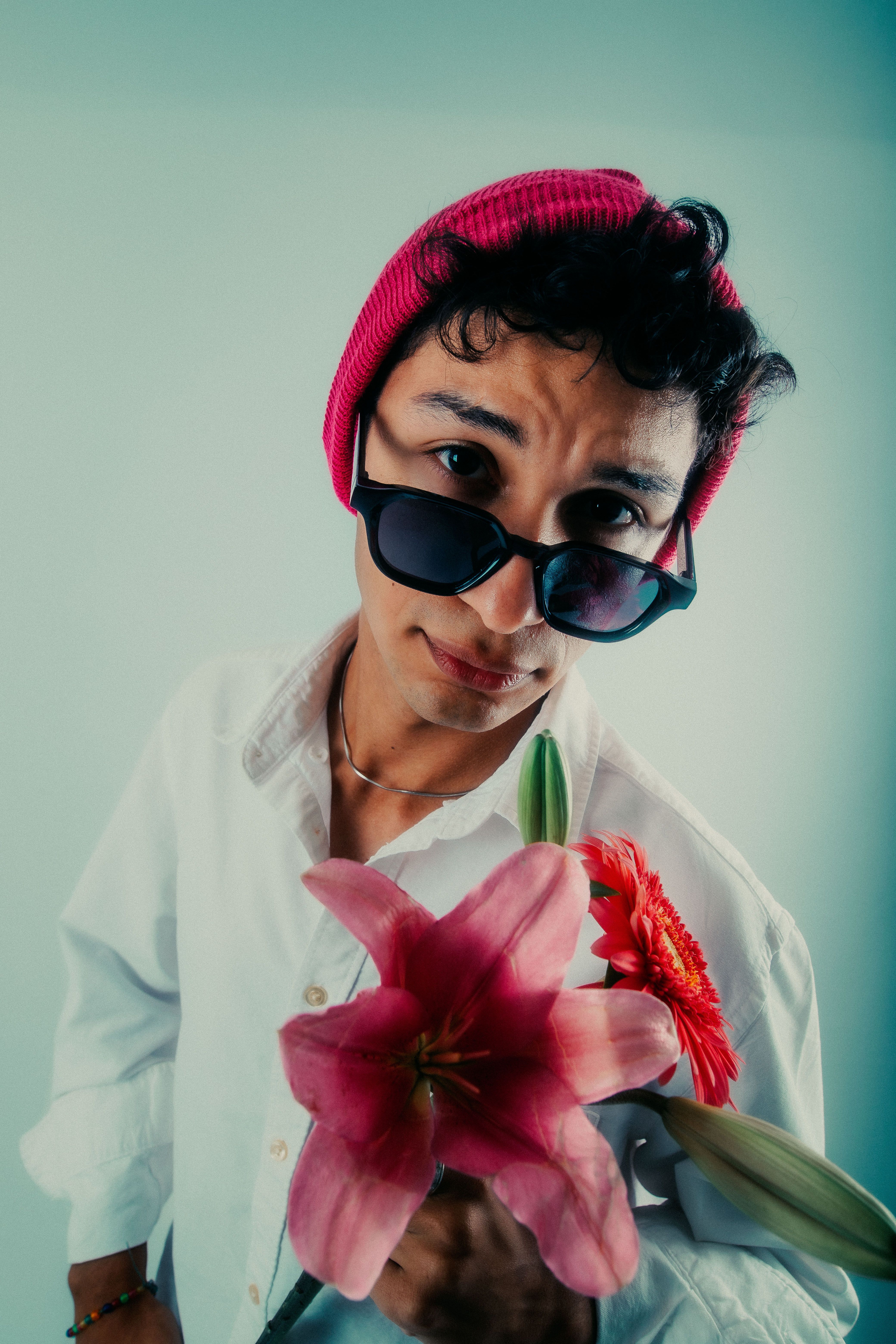 Stylish young man wearing sunglasses and a beanie holds flowers. Captured in Buenos Aires, Argentina.