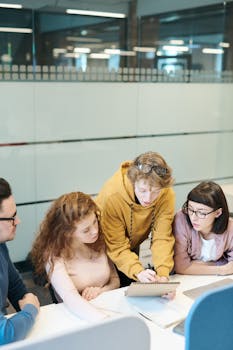 A group of young professionals working together at a modern office with teamwork and discussion dynamics.
