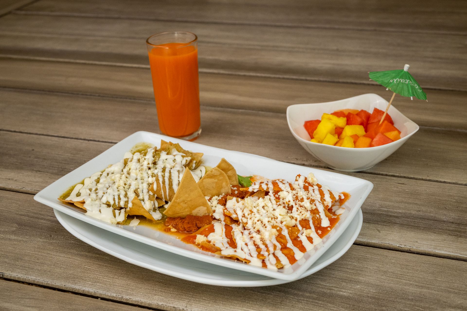 Appetizing Mexican breakfast with chilaquiles, juice, and tropical fruit bowl.