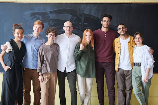 A diverse group of smiling adults posing in front of a chalkboard in an indoor setting.