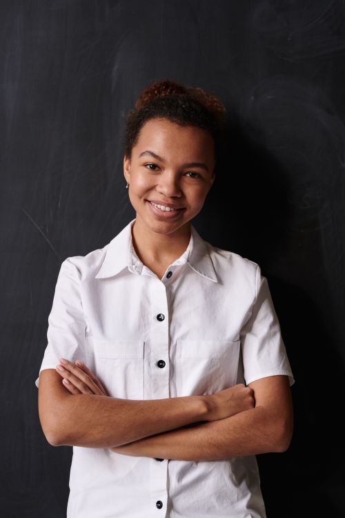 Free Portrait of a smiling woman in a white shirt posing confidently indoors. Stock Photo