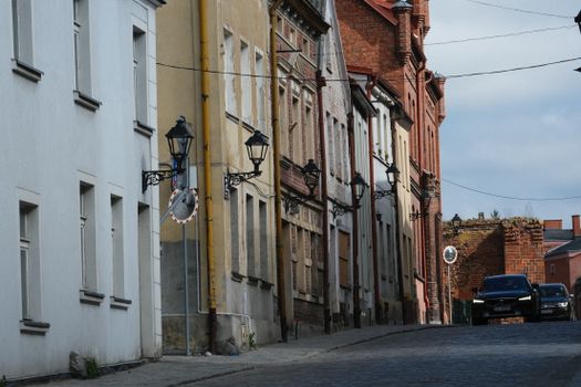 Historic European street lined with rustic buildings and classic street lamps.