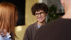 室内，朋友们正在友好交谈，其中有一位卷发戴眼镜的女人