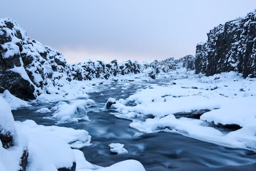 Snow-covered rocky terrain along a serene river in Selfoss, Iceland.
