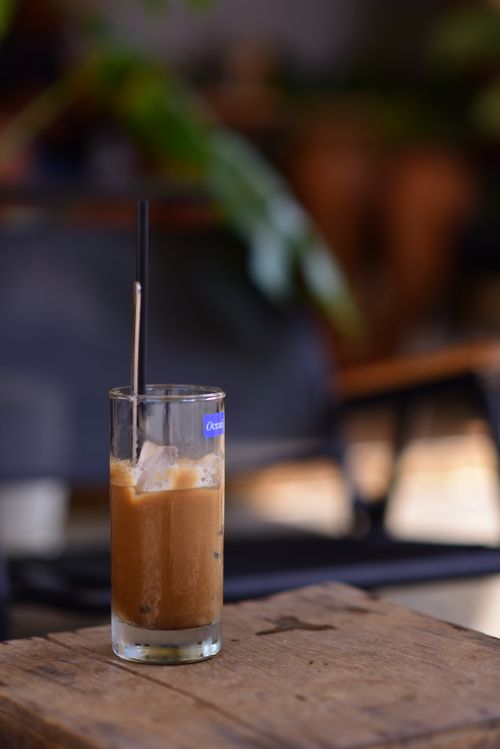 Free A cool glass of iced coffee with a straw on a wooden table in a cozy café, perfect for a summer refreshment. Stock Photo