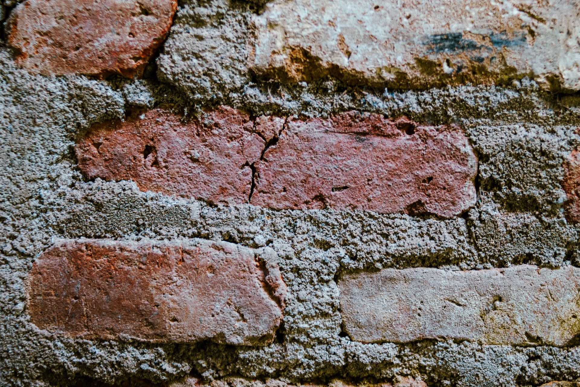 Detailed texture of an outdoor rustic brick wall with visible mortar cracks.