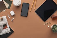 时尚工作区的顶视图，科技小工具和文具置于棕色背景上