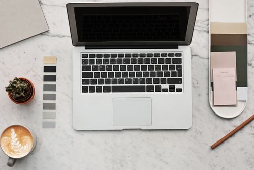 Free Top view of a stylish workspace featuring a laptop, latte, cactus, and color swatches on a marble surface. Stock Photo
