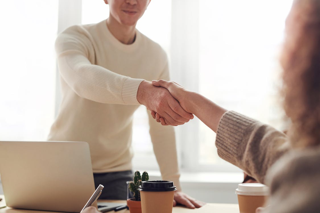 Two people shaking hands across a meeting table