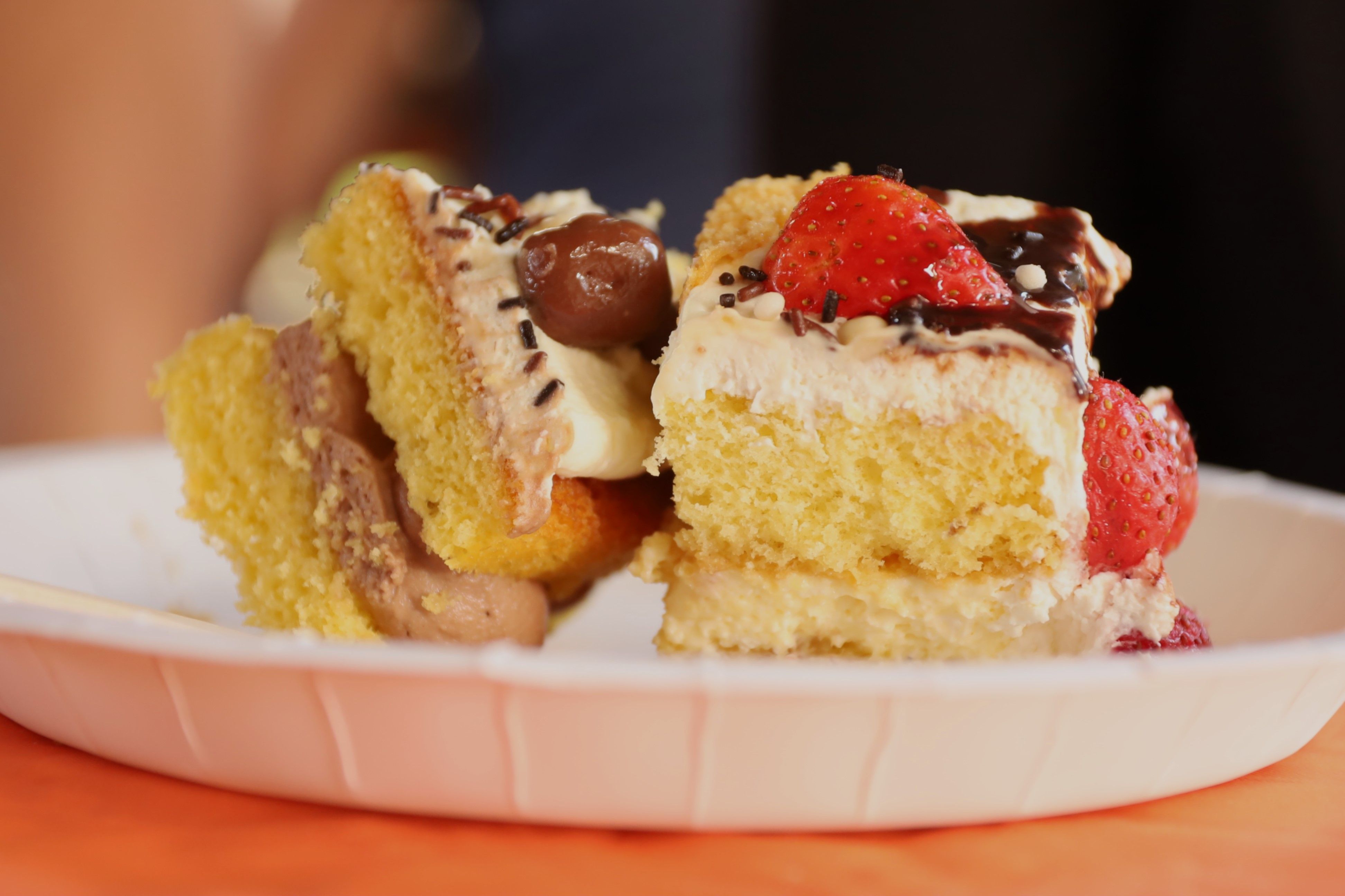 Close-up of a delicious layered cake topped with fresh strawberries and chocolate drizzle.