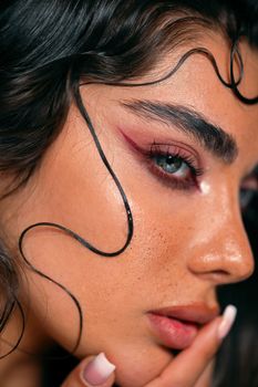 Detailed close-up of a woman's face with artistic styling and bold makeup.