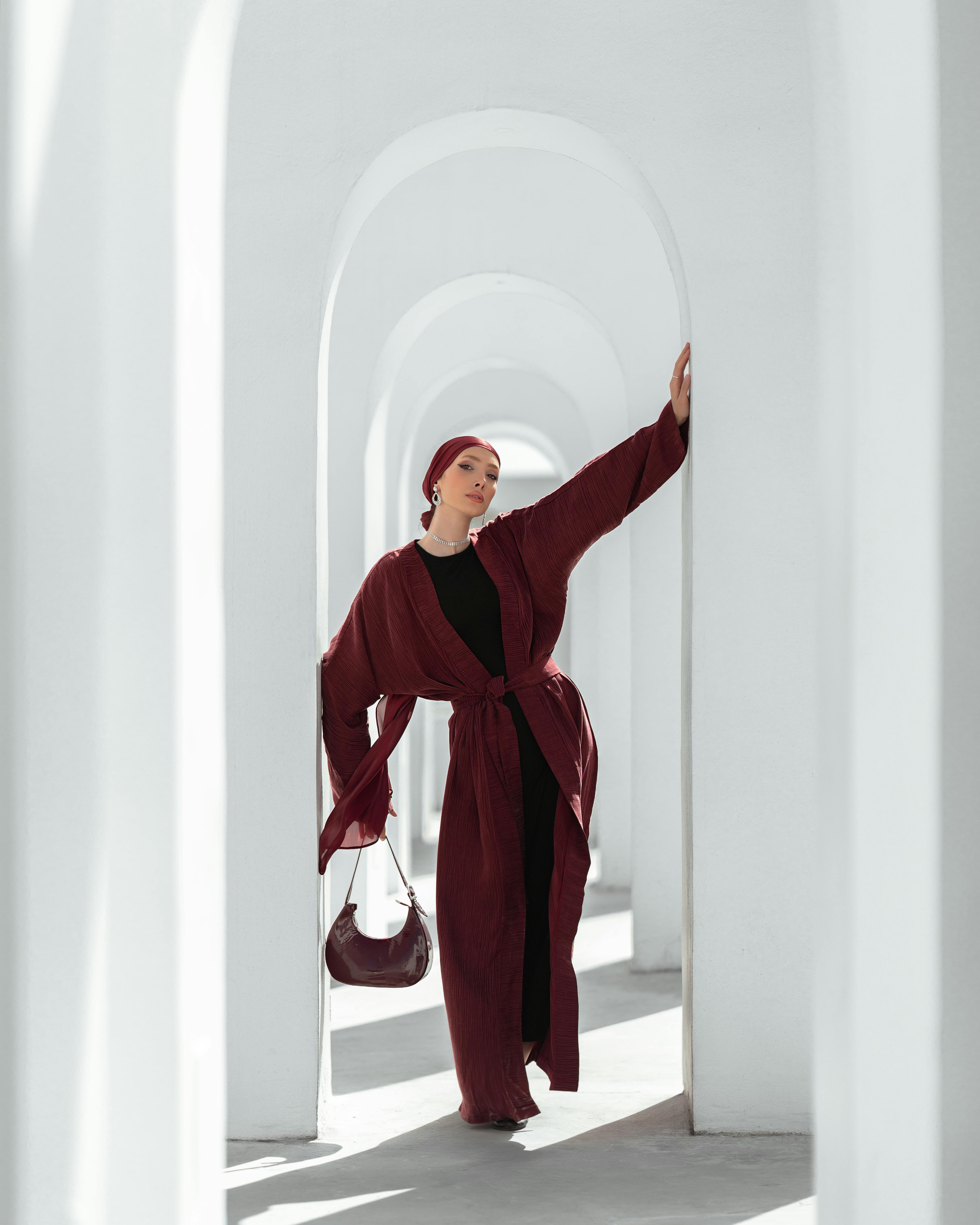 Fashionable woman posing in a modern architectural setting with white arches.
