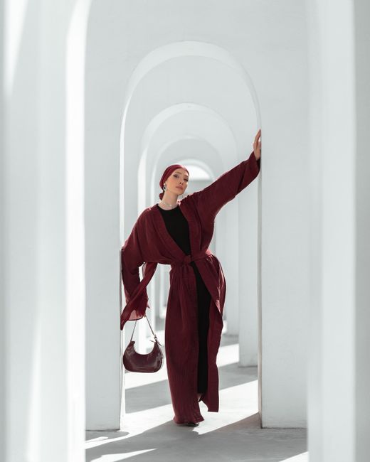 Fashionable woman posing in a modern architectural setting with white arches.