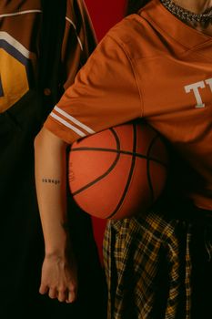 Trendy urban fashion with basketball and tattoos in warm lighting.
