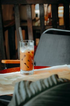 A glass of iced coffee with straw on a cafe table, creating a cozy vibe.