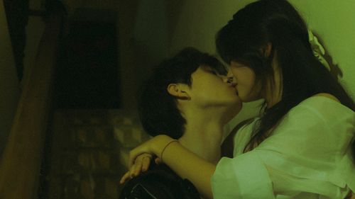 Free A young couple kissing on a dimly lit staircase, capturing a tender romantic moment. Stock Photo