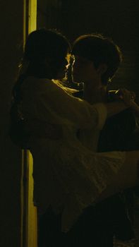 A captivating silhouette of a couple sharing an intimate moment in dim lighting.