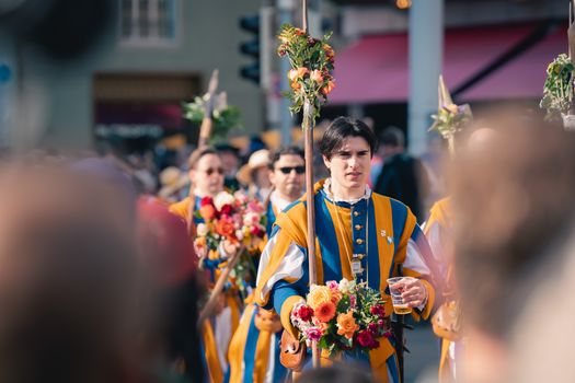 Participants in traditional medieval costumes march in a vibrant outdoor festival parade celebrating cultural heritage.