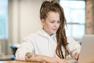 一位留着辫子、纹身的女性在休闲环境中专注于使用笔记本电脑工作