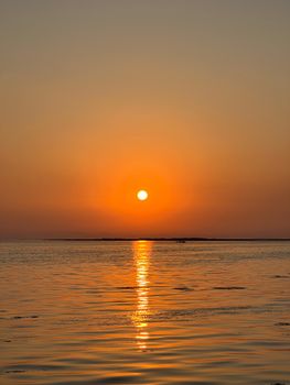 Stunning sunset reflecting over a calm ocean with vibrant orange hues.