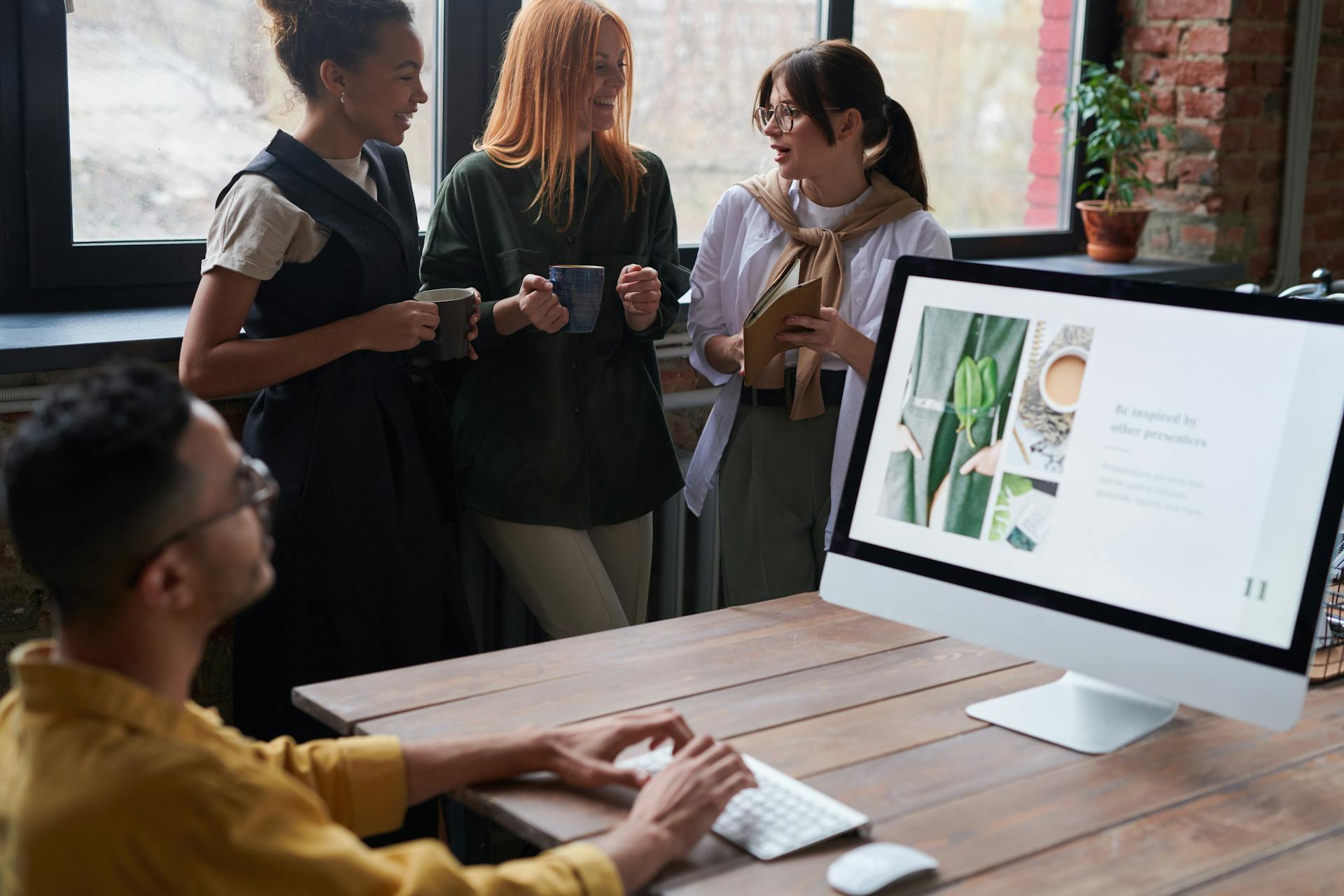 A group of colleagues collaborating in a modern office environment, featuring a computer display and natural lighting.