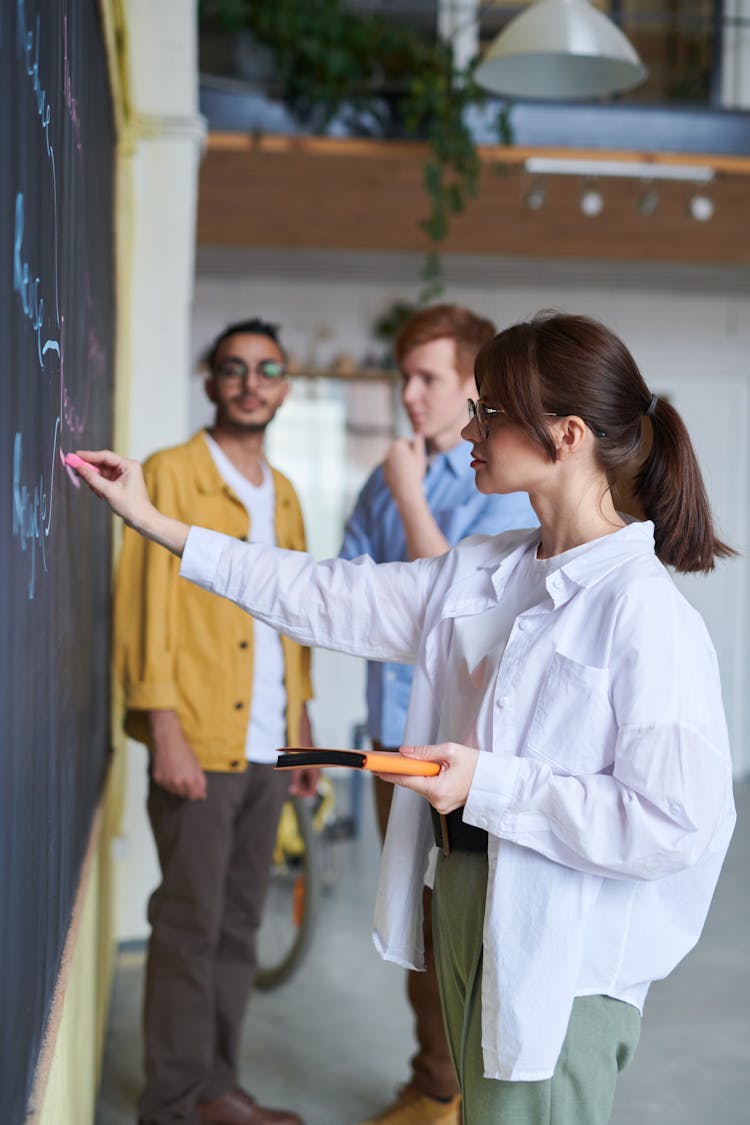 Photo Of Woman Writing On Blackboard