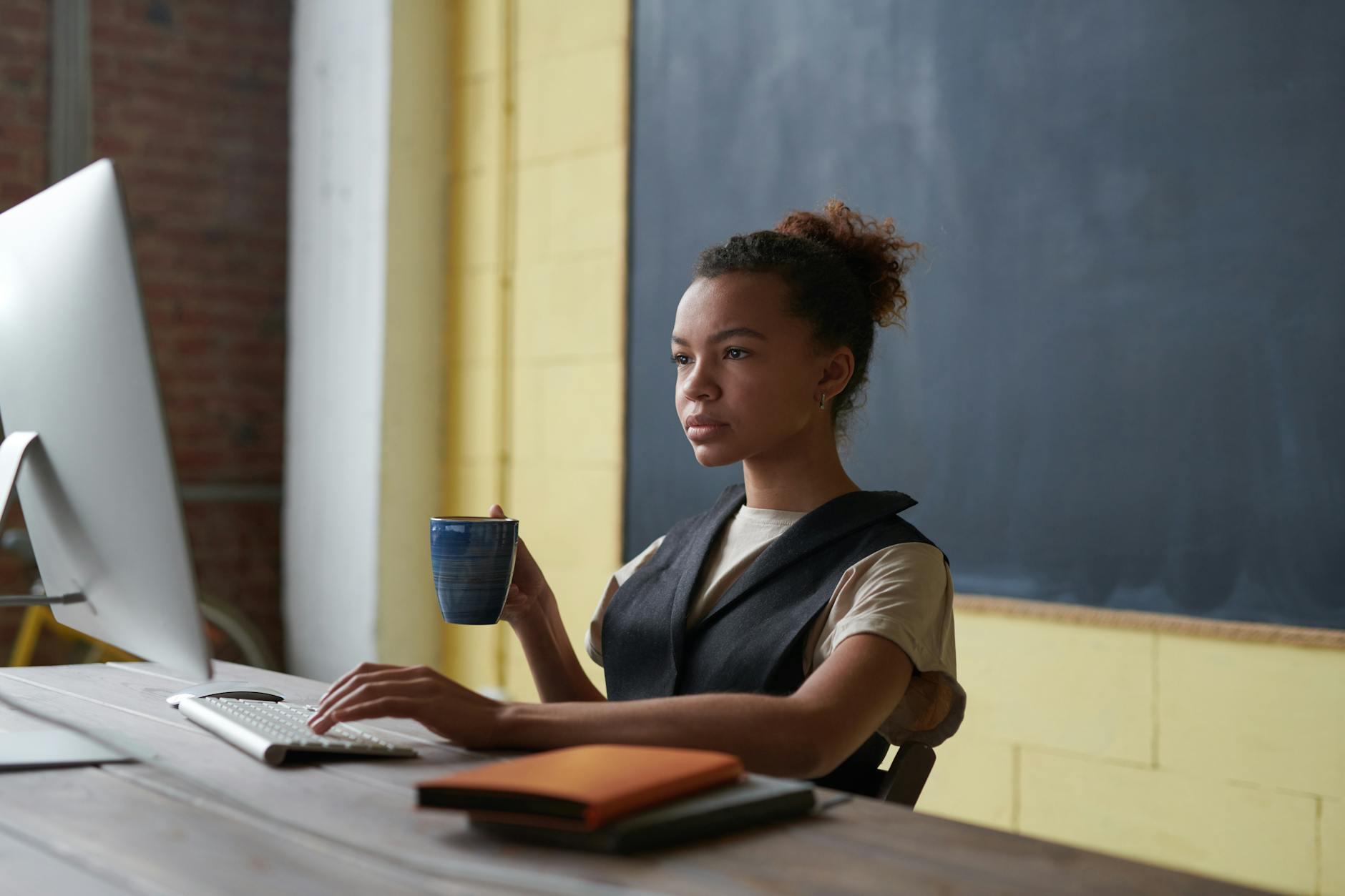 Woman holding a mug while working on a laptop