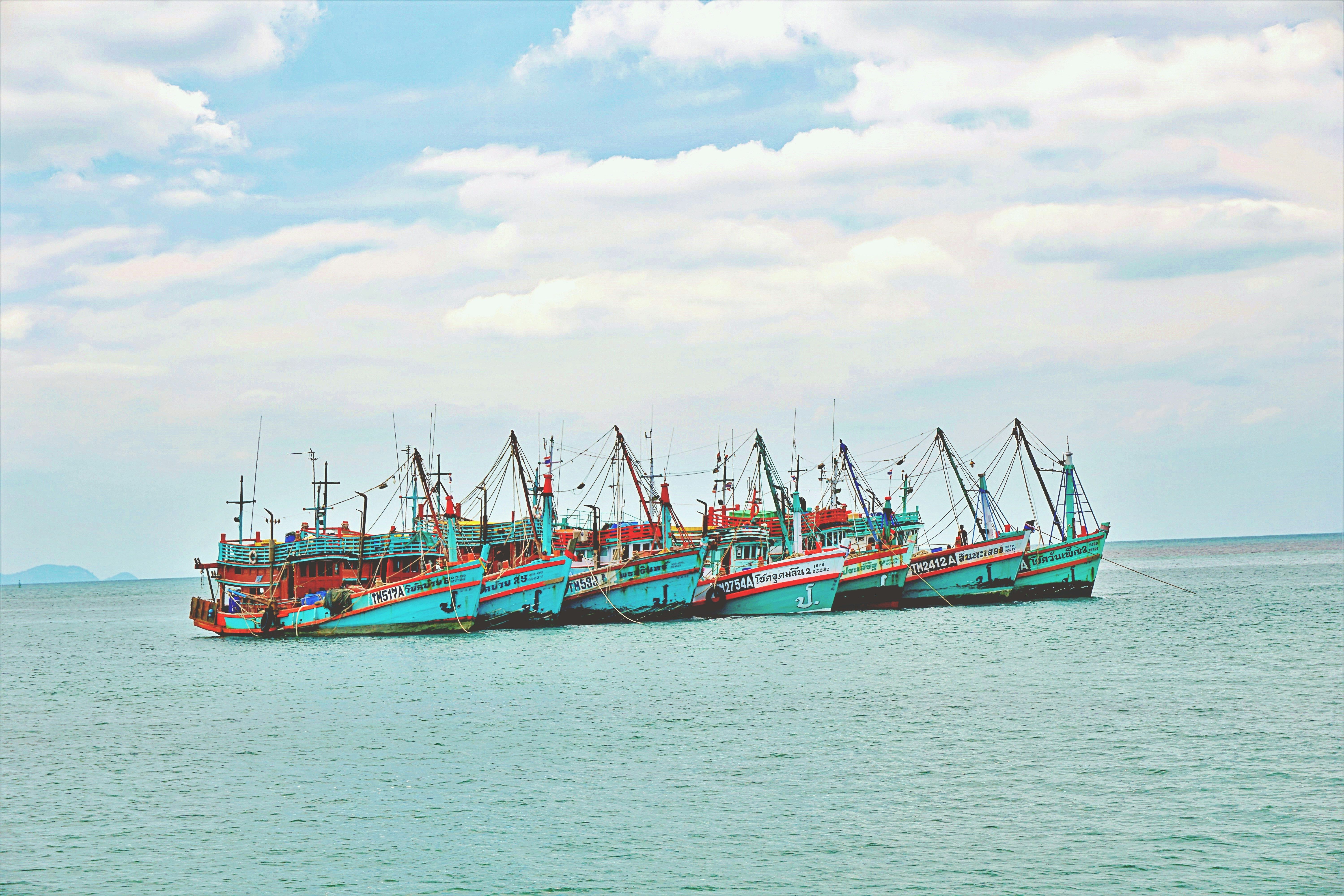 Un groupe animé de bateaux de pêche flottant paisiblement sur le golfe de Thaïlande.