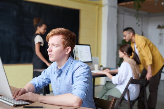 Young professionals deeply engaged in a collaborative office environment, working on digital devices.