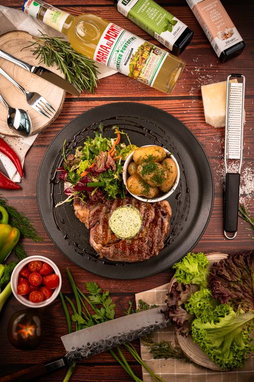 Free A delicious steak meal with salad, potatoes, and fresh ingredients on a wooden table. Stock Photo