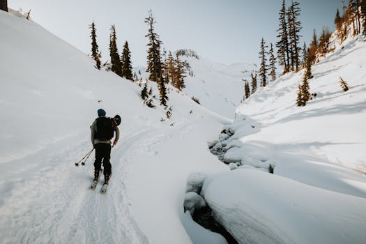 A person skiing and exploring a snowy mountainous terrain under a clear sky.