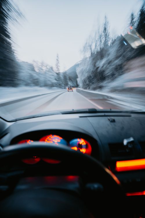 Free Blurred view from a car driving on a snowy mountain road at dusk, capturing speed and motion. Stock Photo