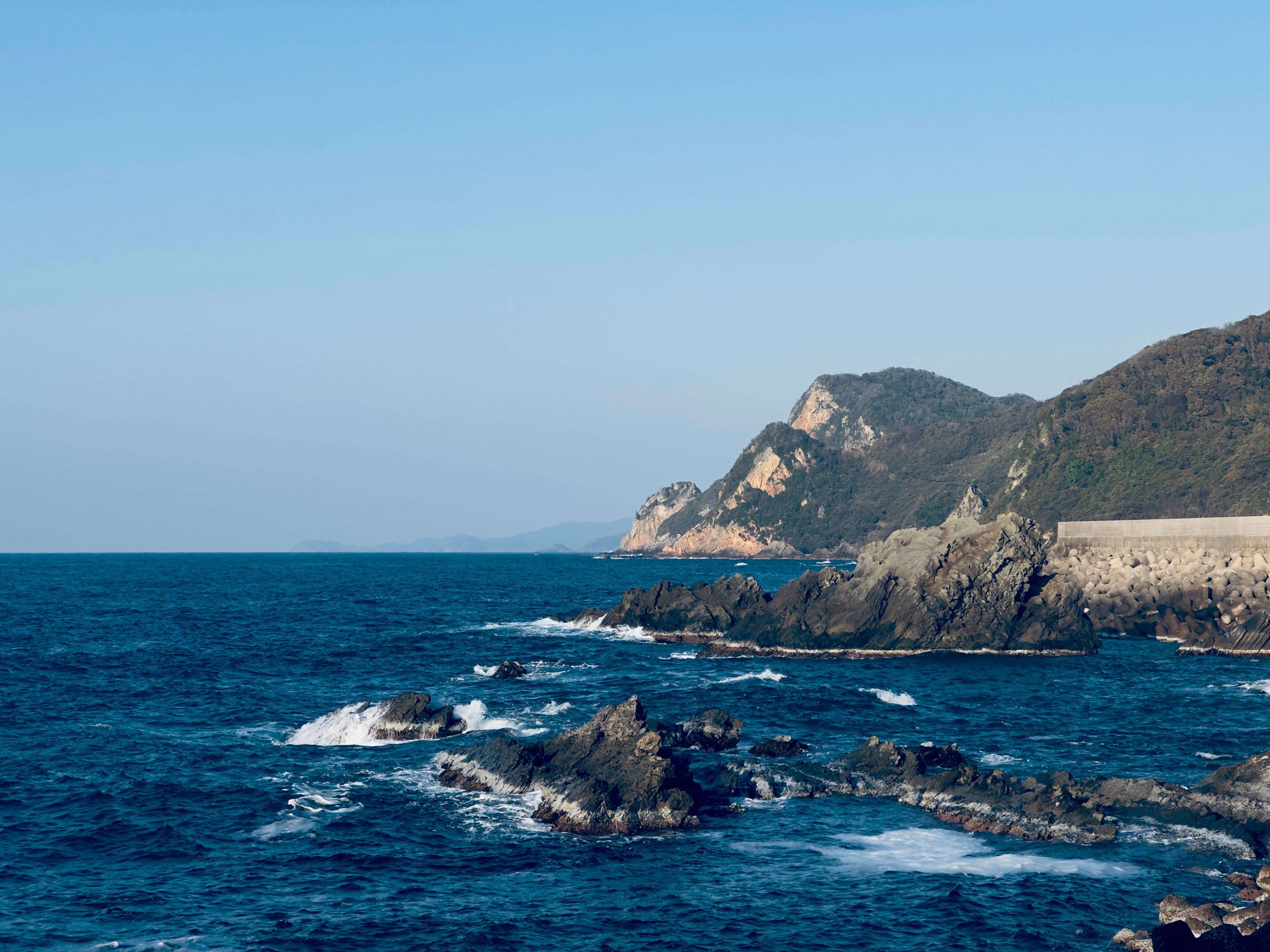 Dramatic coastal scene with rocky shoreline and blue ocean waves.