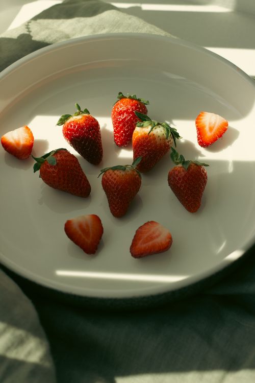 Free Delicious fresh strawberries in gentle sunlight on a white plate, casting natural shadows. Stock Photo
