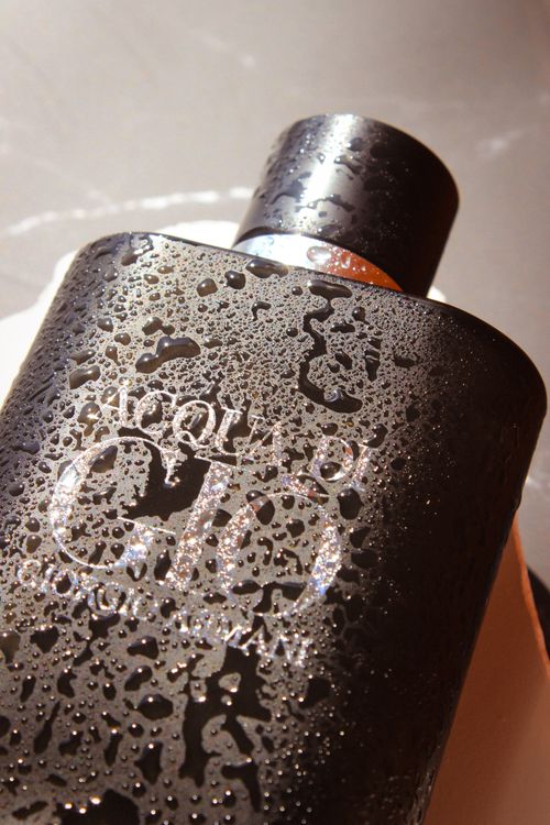 Free Close-up of a sleek black perfume bottle covered with refreshing water droplets. Stock Photo