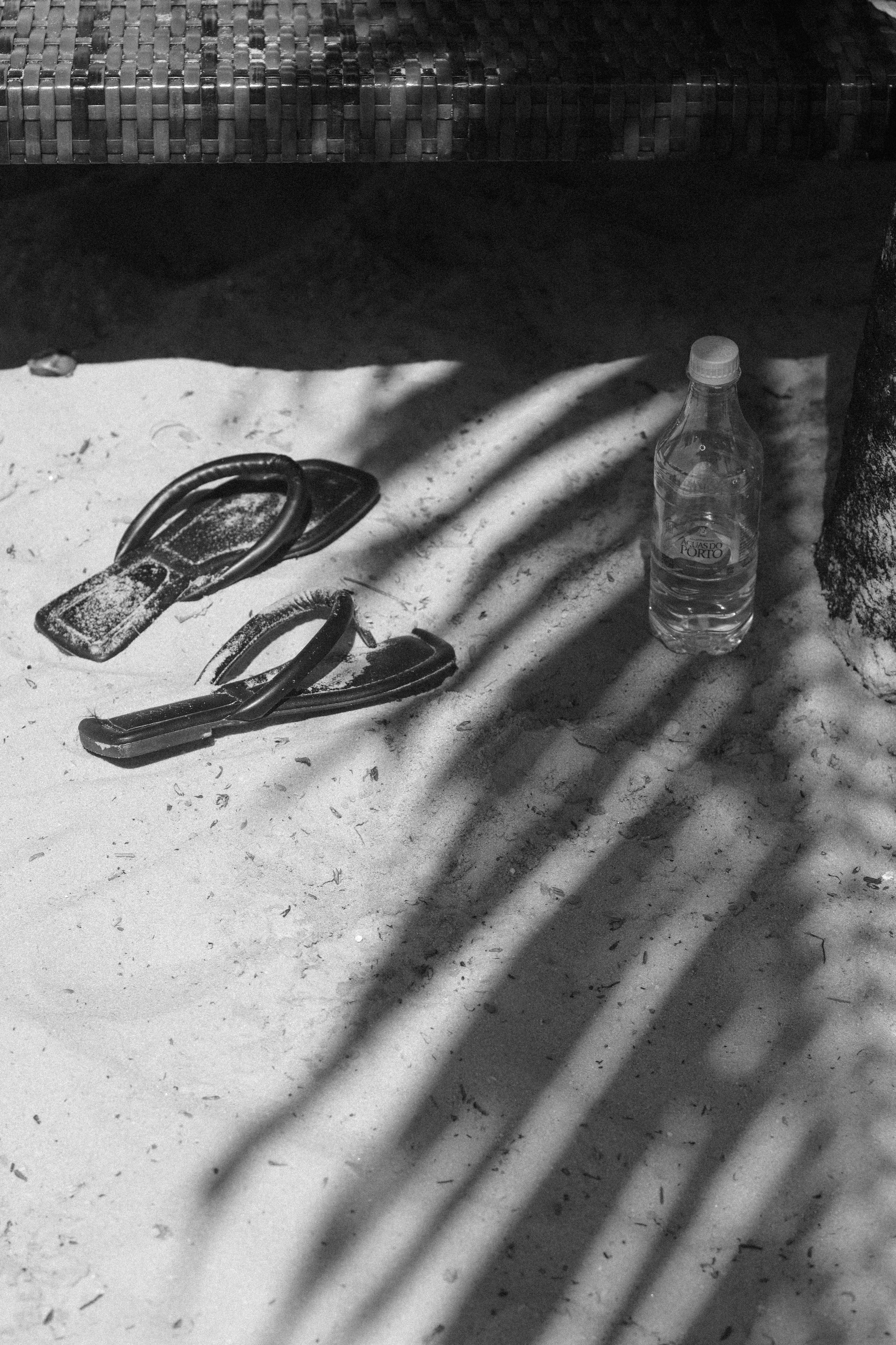 A pair of sandals and a water bottle on sandy beach in Porto Seguro, Bahia, Brazil.