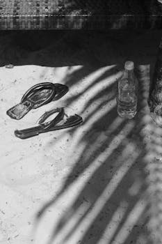 A pair of sandals and a water bottle on sandy beach in Porto Seguro, Bahia, Brazil.