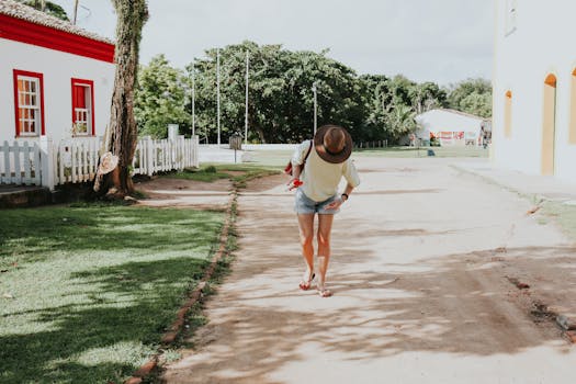A woman in casual attire walks down a sunny street in Porto Seguro, Bahia, Brazil.