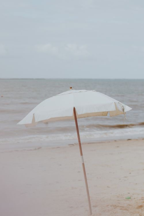 Free Tranquil beach umbrella on the sands of Porto Seguro, Bahia, Brasil against a calm sea. Stock Photo